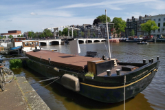 Floden Amstel med husbåten Vriendentrouw i förgrunden och Magere Brug i bakgrunden, Amsterdam.