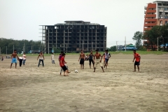 Fotboll på stranden i Cox's Bazar framför ett av många ej färdigställda och övergivna hotell.