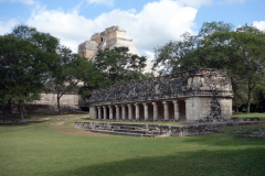 Mindre byggnad med Trollkarlens Pyramid i bakgrunden, Uxmal.