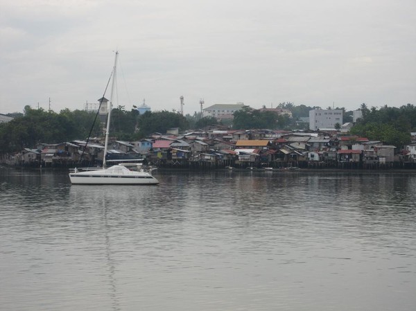 Kontraster med lyxbåt i förgrunden och squatter-bostäder i bakgrunden på Mactan island. Båtresan mellan Ormoc city och Cebu city.