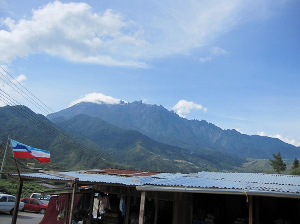 Mount Kinabalu sedd från den lilla byn Kandasan. Till vänster i bild syns Sabah's flagga.