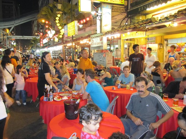 Fullproppat med västerlänningar i chinatown som äter middag på gatan.