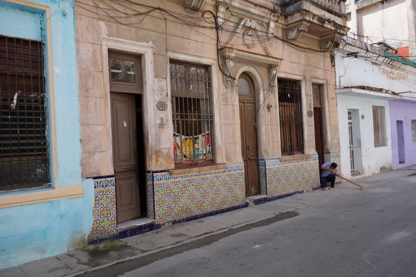 Fin fasad med man till höger i bild som jobbar på ett trästycke av något slag. Centro Habana, Havanna.