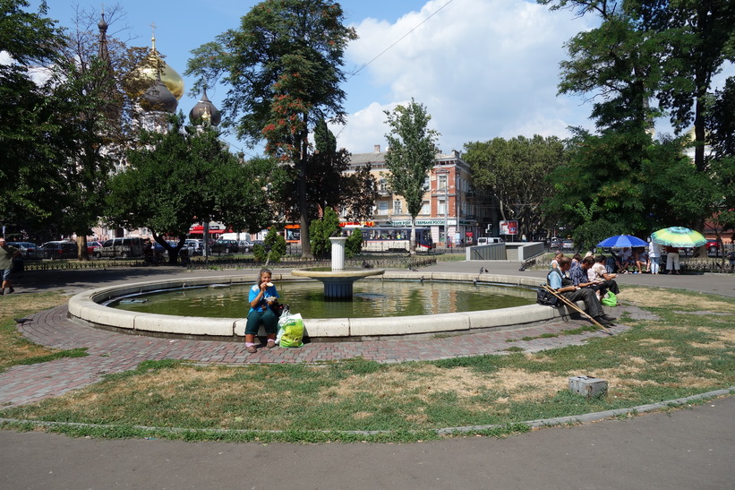 Människor som sitter runt dammen och äter av maten de fått och så väl behövde, Odessa.