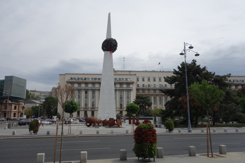 Piata Revoluției med kommunisthögkvarteret i bakgrunden, Bukarest. Det vita pelaren är ett minnesmonument för revolutionens offer.