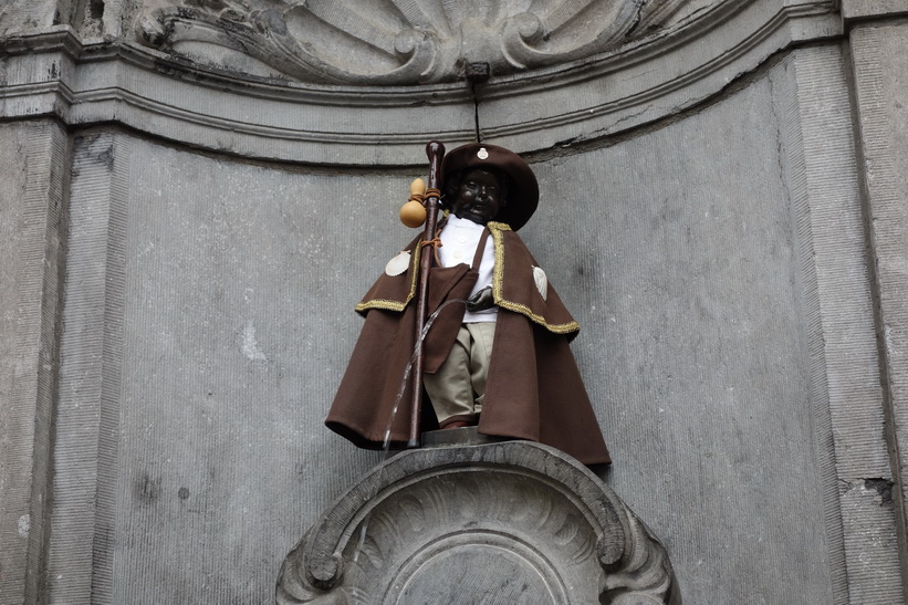 Manneken Pis, det kända landmärket i Bryssel. En liten bronsfontänskulptur föreställande en naken pojke som urinerar i fontänens bassäng. För att skyla den nakna pojken så klär man på honom. Kläderna byts ofta.