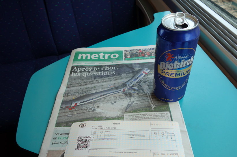 Avnjuter en Luxemburgsk öl i väntan på att tåget ska börja rulla mot Bryssel från stationen i Luxemburg city. På bordet har jag dagens upplaga av tidningen Metro som har den fruktansvärda tågolyckan från igår på hela förstasidan.