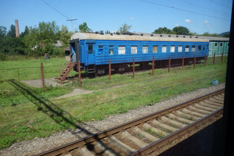 En tågstation med en gammal tågvagn som är tagen ur bruk. Tågresan mellan Lviv och Uzhhorod.