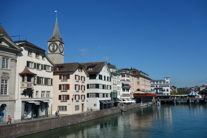 Vacker arkitektur vid floden Limmat med klocktornet på St. Peterskirche i bakgrunden, Zürich.