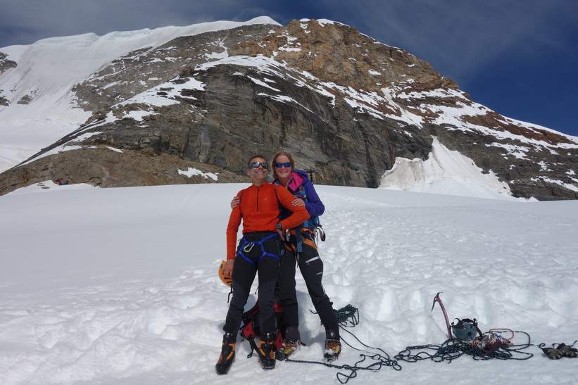 Schweiziskt överlyckligt par som precis har bestigit Mönch för första gången. Promenaden från Mönchsjochhütte tillbaka ner till Jungfraujoch.